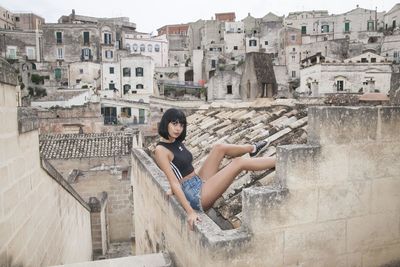 Woman sitting against buildings in city