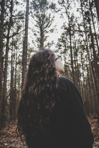 Rear view of young woman standing in forest