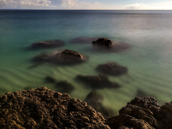 Scenic view of rock formation in sea against sky