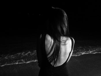 Rear view of woman standing at beach