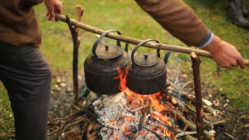 Midsection of man preparing food over bonfire