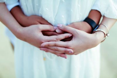 Midsection of pregnant couple touching abdomen