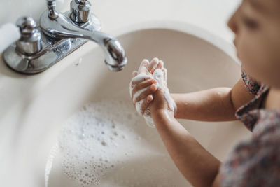 High angle view of young girl washing hands in sink with soap