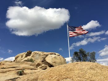 Low angle view of flag on rock against sky