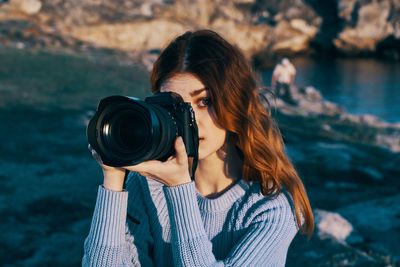 Portrait of young woman photographing camera