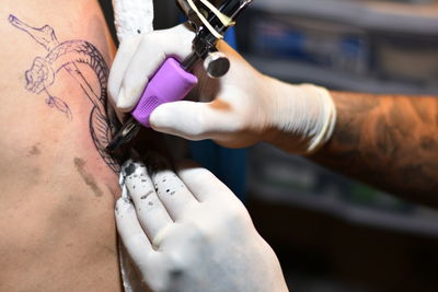 Cropped hand making statue on customers abdomen