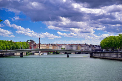 Bridge over river against cloudy sky