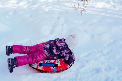 Child in violet clothes ride on tubing. winter activities for children