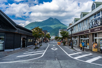 Road by buildings in city against sky