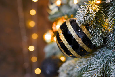 Gold and black christmas ornament hanging on the tree with blurred background