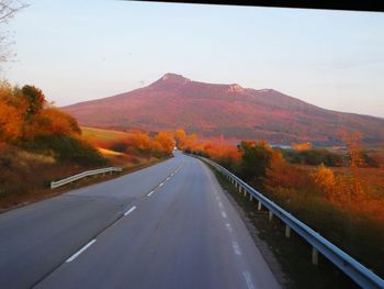 Road amidst mountains against clear sky during autumn