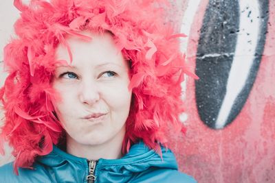 Close-up of woman making face while wearing feathers