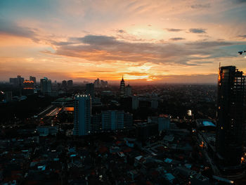 Illuminated cityscape against sky during sunset