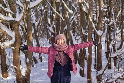 Full length of woman standing on snow covered plants during winter