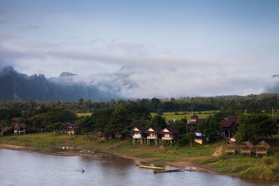 Scenic view of river by buildings against sky