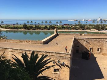 High angle view of people on historic building terrace by sea against clear sky
