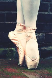 Low section of ballet dancer against wall
