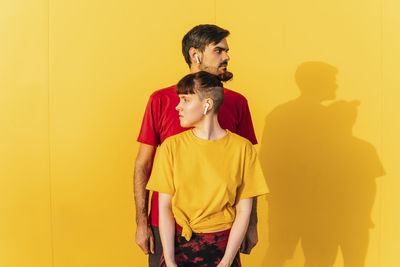 Young man standing against yellow wall