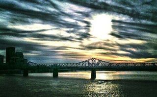 Bridge over river against cloudy sky