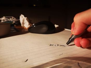 Close-up of hand holding book with text on table