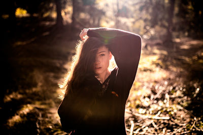 Portrait of woman standing by tree in forest