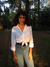 Portrait of smiling young woman standing in forest
