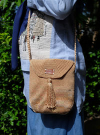 A brown kniting sling bag worn by a woman.
