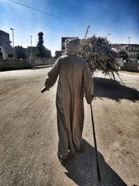 Rear view of man walking on footpath in city