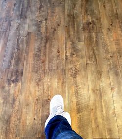 Low section of man standing on hardwood floor