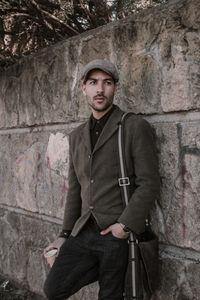 Portrait of young man standing against wall