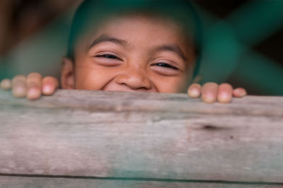 Close-up portrait of boy hiding behind table