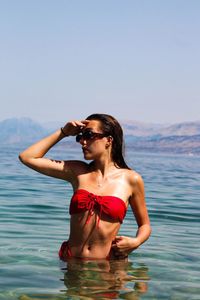 Young woman standing in sea against sky