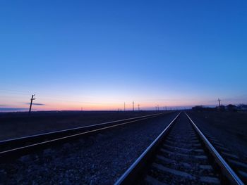 Railroad tracks against clear sky at sunset