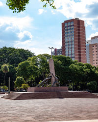 Statue in park against sky in city