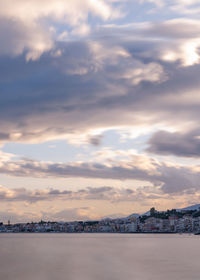 Scenic view of sea and buildings against sky during sunset