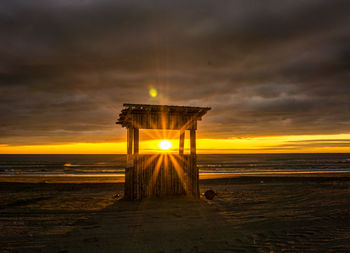 Lifeguard hut on beach against sky during sunrise