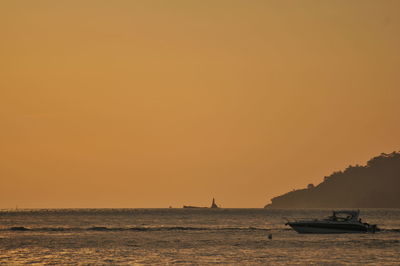 Boats sailing in sea against orange sky
