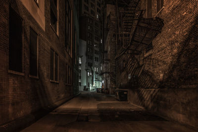 Empty alley amidst buildings at night