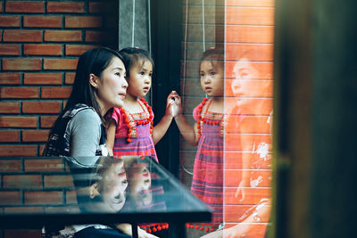 Mother with baby girl standing by window