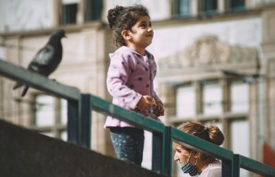 Girl looking away while standing on railing