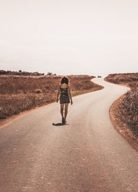 Rear view of woman walking on road against sky