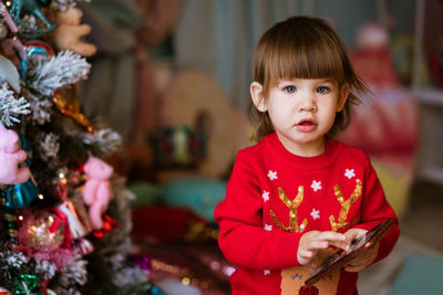 Happy little girl in a red sweater, joyfully holding the phone, near