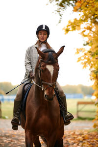 Portrait of woman riding horse on field