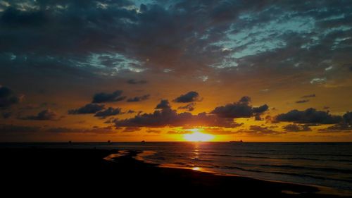 Scenic view of sea against dramatic sky during sunset