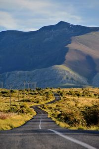 Road leading towards mountains against sky