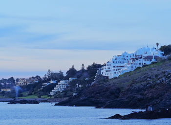 Buildings by sea against sky