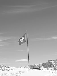 Flag on snow covered landscape against clear sky