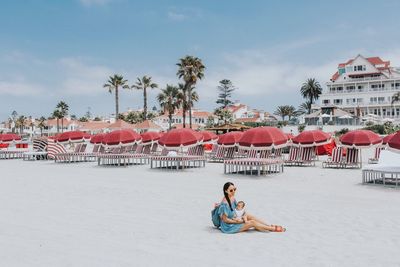 Man sitting on beach against sky