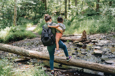 Full length of mother and daughter walking in forest