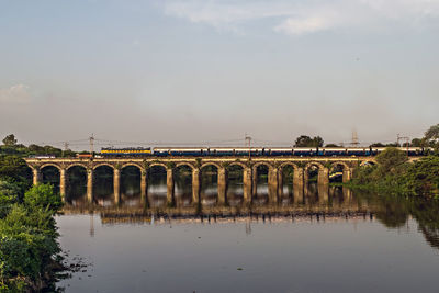 Arch bridge over river against sky